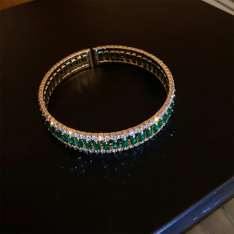 Elegant emerald and diamond tennis bracelet on black surface, luxury fashion accessory