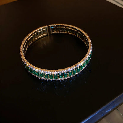 Elegant emerald and diamond tennis bracelet on black surface, luxury fashion accessory