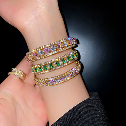 Elegant gold bangles with colorful gemstones and crystals, perfect for fashion jewelry lovers.