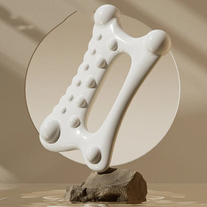 White ergonomic massage tool with nodules for muscle relief, displayed on stone base with water ripples