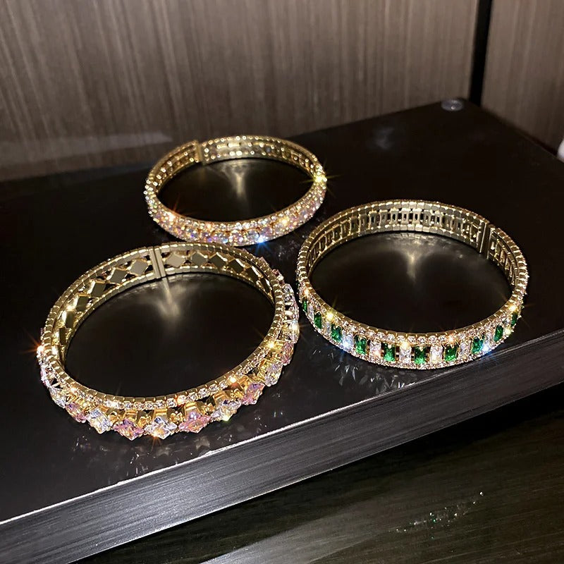 Elegant gold bangles with sparkling crystals and emerald accents, perfect for fashion jewelry lovers.