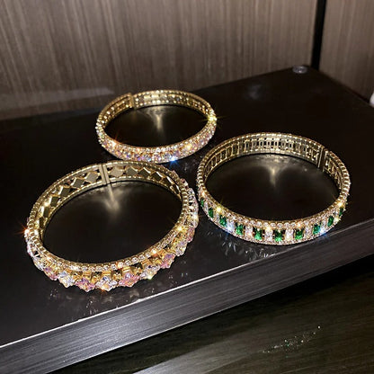Elegant gold bangles with sparkling crystals and emerald accents, perfect for fashion jewelry lovers.