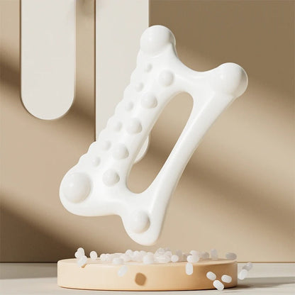 White ergonomic massage tool with textured nodules for muscle relief, displayed on beige stand