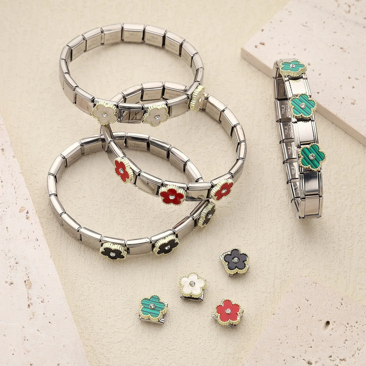 Stainless steel flower charm bracelets with interchangeable red, white, black, and green enamel charms for women's fashion jewelry.