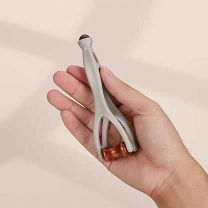Hand holding gray and wood-handled massage tool for muscle relief