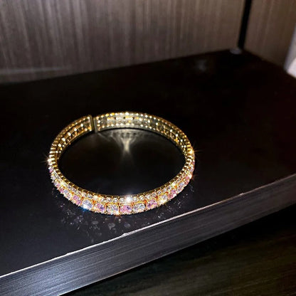 Elegant gold bangle bracelet with sparkling pink and clear crystals, perfect for fashion accessories.