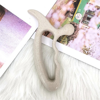 Beige ergonomic massage tool on fluffy white surface with photo prints, ideal for home wellness and relaxation.