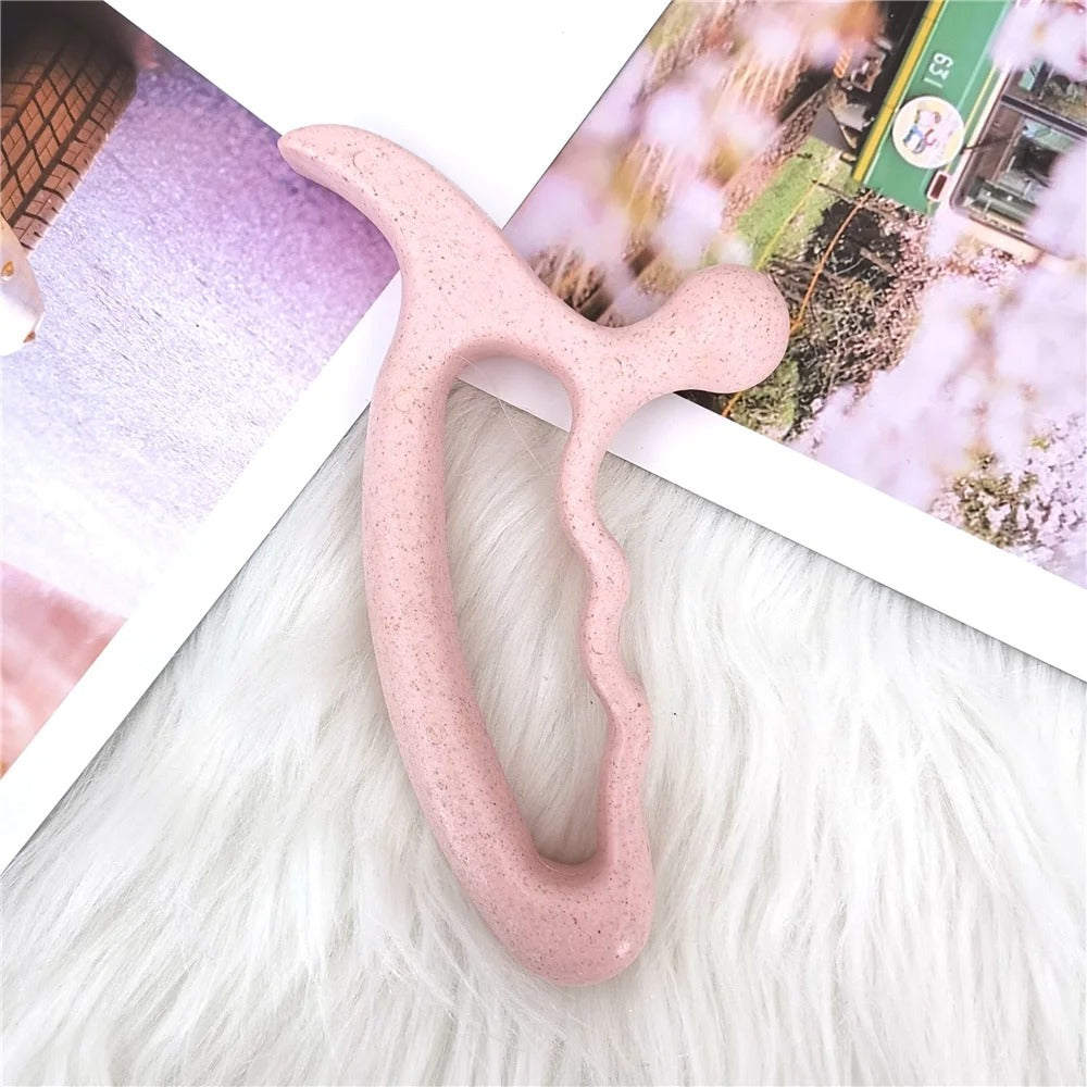 Pink ergonomic face massager tool on fluffy white surface with magazine backdrop